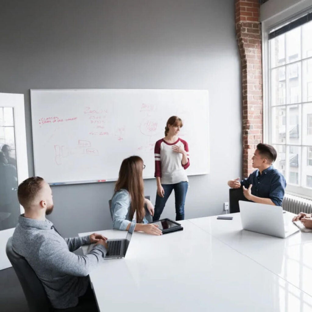 People working in a conference room in front of a whiteboard.