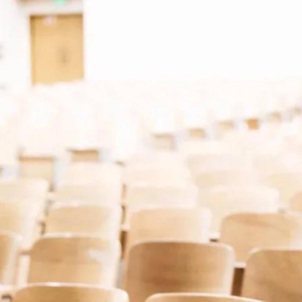 Empty rows of wooden chairs.